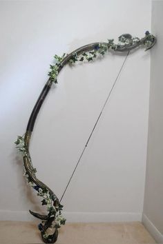 an artistic bow with flowers and leaves on the top is displayed in front of a white wall