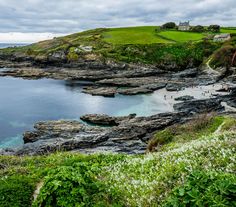 the coast is surrounded by rocky cliffs and green grass