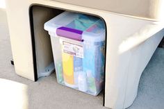 a plastic container is sitting on the floor next to a shelf with some containers in it