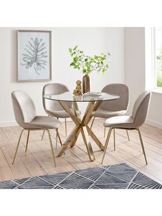 a glass table with four chairs and a rug on the floor in front of it