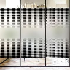 a room divider with black and white dots on the glass doors, in front of a bookshelf