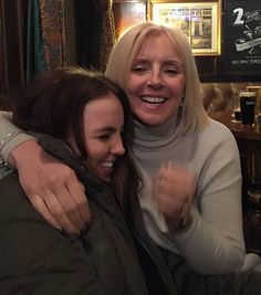 two women hugging each other in a bar