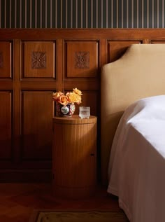 a bed sitting next to a wooden headboard with flowers on it's night stand