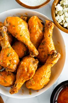 chicken wings in a white bowl next to other foods