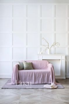 a living room with a pink couch and white paneling on the wall behind it