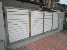 a white fence is next to a brick walkway