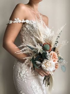 a woman in a wedding dress holding a bridal bouquet with feathers and flowers on it