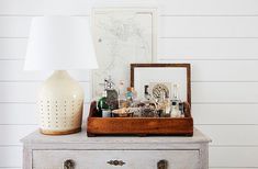 an old dresser with liquor bottles on it and a lamp in the corner next to it