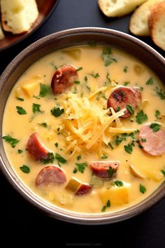 a bowl of soup with sausage, cheese and bread