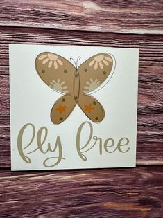 a close up of a sign on a wooden surface with a butterfly painted on it