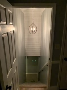 an open door leading to a bathroom with a light hanging from the ceiling above it