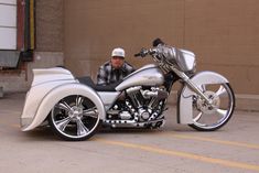 a man sitting on top of a silver motorcycle parked in front of a garage door