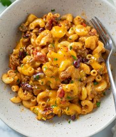 a white bowl filled with macaroni and cheese on top of a marble table