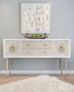 a white table with two drawers and a painting on the wall