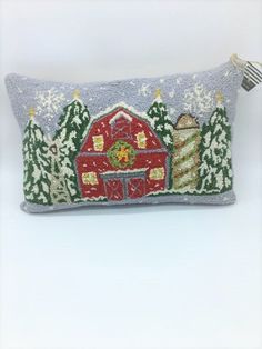 an embroidered pillow with a barn and trees on it