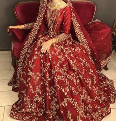 a woman sitting on top of a red couch wearing a dress and headdress