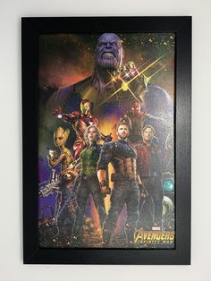 the avengers movie poster is hanging on the wall in front of a black framed frame