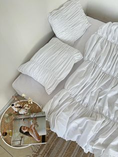 a bed with white sheets and pillows on top of it next to a table with flowers