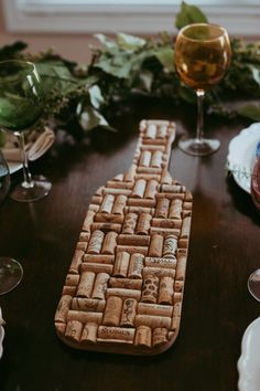 a wooden table topped with wine glasses next to a cork board on top of it