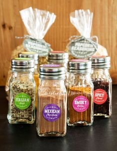 four jars filled with spices sitting on top of a table