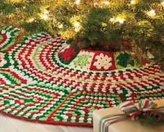 a crocheted christmas tree skirt with presents under it