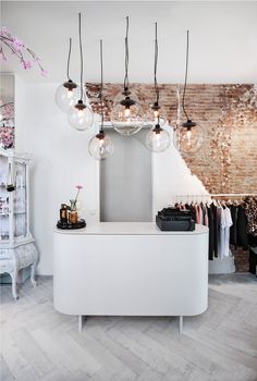 an image of a white counter with lights hanging from it's ceiling and on the wall