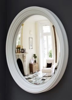 a living room filled with furniture and a fire place in front of a round mirror