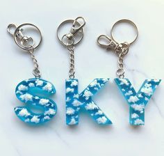 three key chains with the letters sky and clouds on them