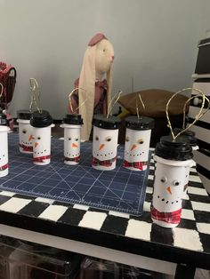 several coffee cups are sitting on a table with a snowman figure next to them