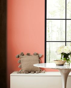 a white table sitting next to a window in a room with pink walls and furniture