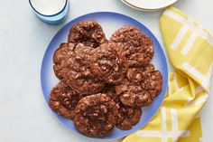 chocolate cookies on a blue plate next to a glass of milk