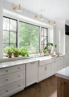 a kitchen filled with lots of white cabinets and counter top space next to a window