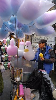 a man is selling balloons and other items at an outdoor vendor's stall in the city