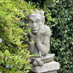 a statue sitting in the middle of some bushes