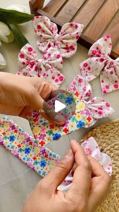 someone is cutting fabric with scissors on a table next to flowers and other items that are being made