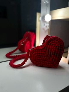 a red purse sitting on top of a white table next to a light bulb and lamp