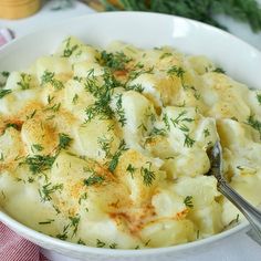 a white bowl filled with potatoes covered in cheese and herbs