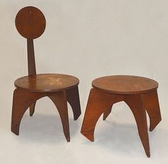 two wooden chairs sitting next to each other on a white surface with one chair facing the other