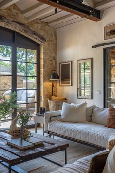 a living room filled with furniture and windows next to a stone wall covered in plants