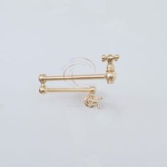 two gold - plated metal objects on a white surface, one has an earring and the other is a nose ring