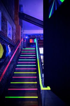 colorful stairs lit up with neon lights in a dark room at the bottom of it