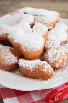 powdered sugar covered donuts on a plate with red and white checkered napkin