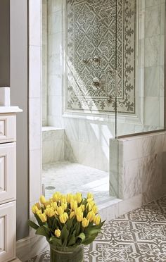 a vase with yellow tulips sits on the floor in front of a shower