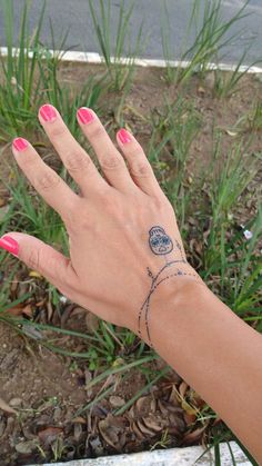 a woman's hand with a small tattoo on her left wrist and pink nail polish