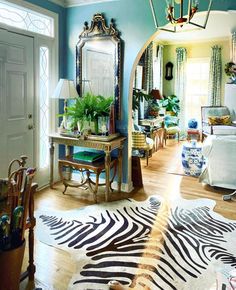 a living room with blue walls and zebra print rugs on the wooden flooring