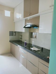 a kitchen with white cabinets and black counter tops is shown in this image, there are papers on the counter