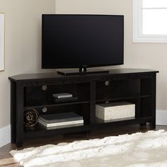 a flat screen tv sitting on top of a wooden entertainment center next to a window