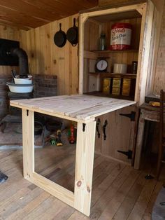 a wooden table sitting inside of a kitchen next to a brick oven on top of a hard wood floor