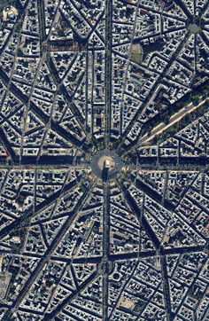 an aerial view of a city with lots of buildings and roads in it, looking down at the ground