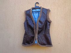 Women's outdoor sleeveless vest. Women's brown vest. Warm brown leather vest. Elegant sleeveless jacket. Faux fur sleeveless vest.  The vest is made to order in Bulgaria. The outer part is made of face brown artificial leather. The inside is lined with light blue artificial silk.  From the waist to the hips it is beautiful flared to discreetly cover the hips. There is a sewn-in wire button at the waist. It was made in Bulgaria and has never been used. FLAT Measurements Back Width - 47cm (18.50") bust width -  48 cm (18.90") length from neck to end of back - 60 cm (23.70") Shoulder to shoulder distance 40 cm (15.75")  Weight 360g Thank you for visiting! If you have time, please check out my other store! https://www.etsy.com/shop/oldarticlesbg Cheap Brown Sleeveless Vest, Brown Vest Women, Brown Leather Vest, Brown Vest, Sleeveless Jacket, Leather Vest, Warm Brown, Women's Costumes, Sleeveless Vest